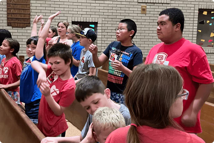 Kids raising their hands to ask questions during a youth program at St. Paul Lutheran Church